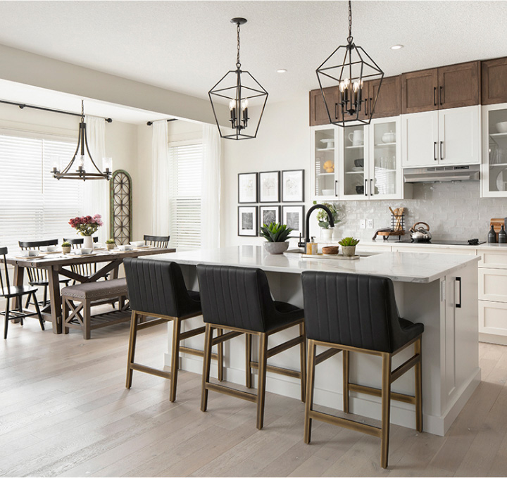 Beautifully decorated, modern kitchen with iron lanterns and black stools at the light stone island.