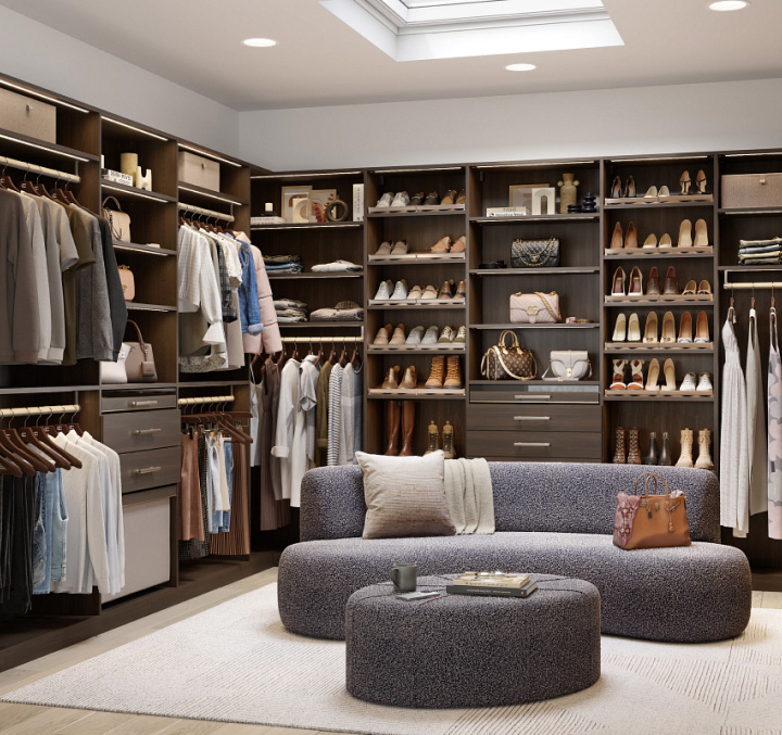 A large walk-in closet with shelves, cabinets and hanging space, complete with a small sofa in the centre.