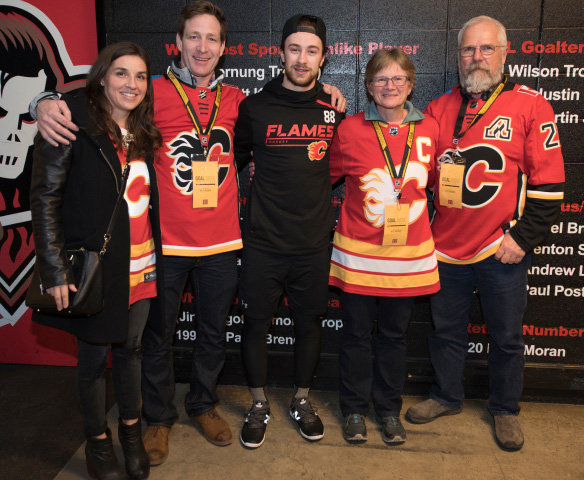 Five individuals posing for a photo wearing Calgary Flames jerseys.