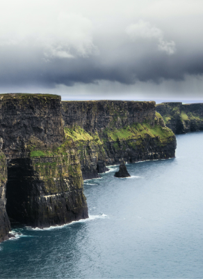 The cliffs of Moher in Ireland with dark grey clouds above.