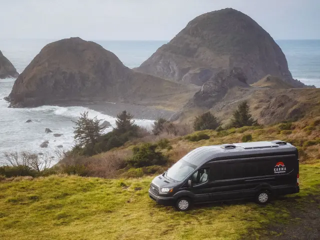 Camper van parked on a sandy beach with ocean waves in the background, offering a scenic and idyllic setting for a beachside adventure.